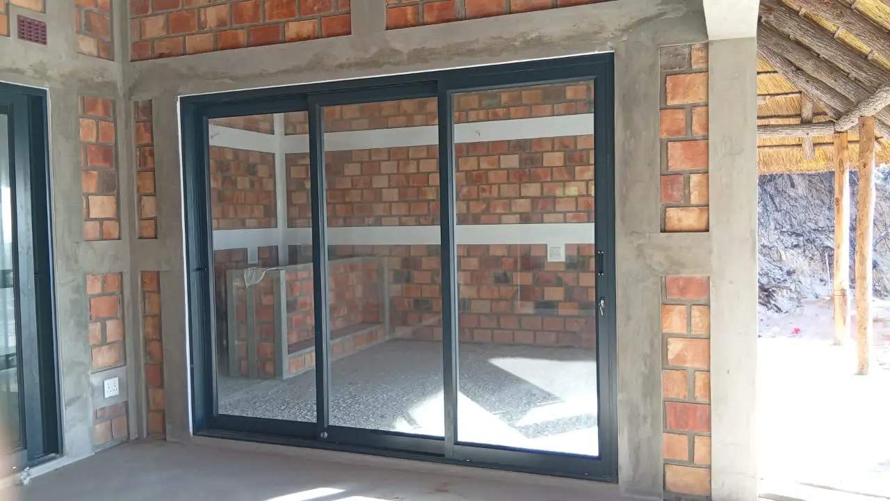 Black aluminium sliding doors set into a brick and timber interior