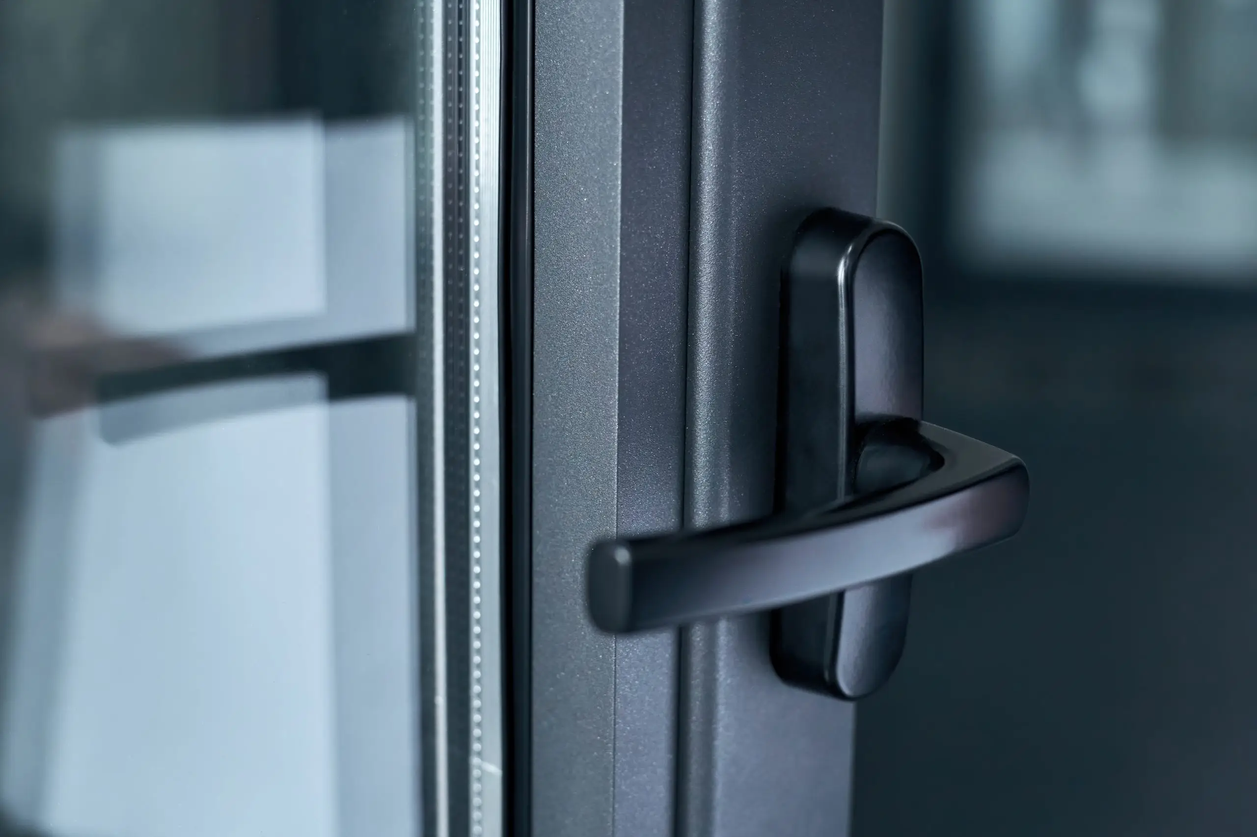 Close detail of a black aluminium door handle and glazed frame